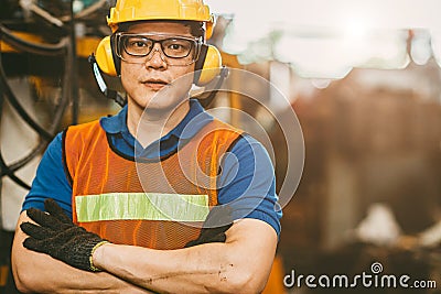 Asian engineer worker wearing earmuffs ears protection anti noise and safety suit working in factory portrait Stock Photo