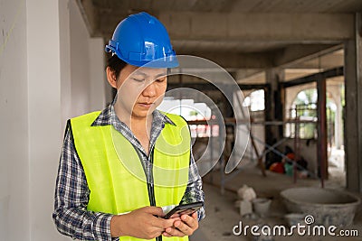 Asian engineer, Young Architect or contractor put on a helmet for safety and use smart phone for take picture and send Stock Photo