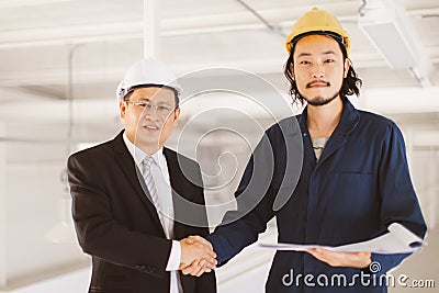 Asian engineers standing hand shake to successful in work Stock Photo