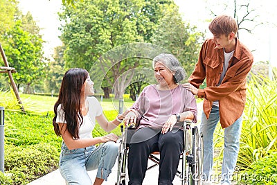 grandson and granddaughter Take grandma in a wheelchair for a walk in the park. Stock Photo