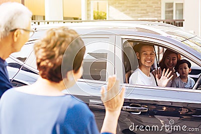 Asian family of father, mother and son waving goodbye to grandfather and grandmother as they take off their journey. Stock Photo