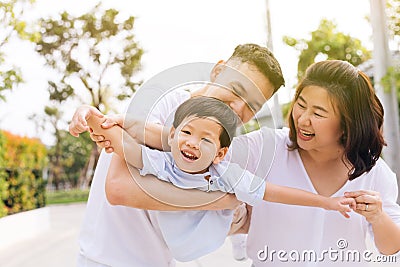 Asian family having fun and carrying a child in public park. Stock Photo