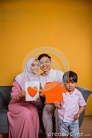 Asian family showing a paper love drawing and home shapes Stock Photo