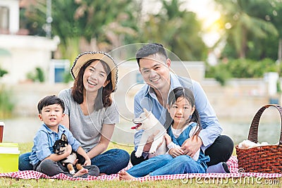 An Asian family plays with a Shiba Inu dog. Family has father, mother and son, daughter. Picnicking in the garden Stock Photo