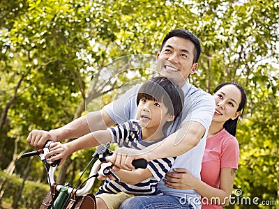 Asian family riding bike in park Stock Photo