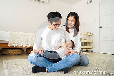Asian family of young father and mother feeding a baby boy from milk bottle Stock Photo