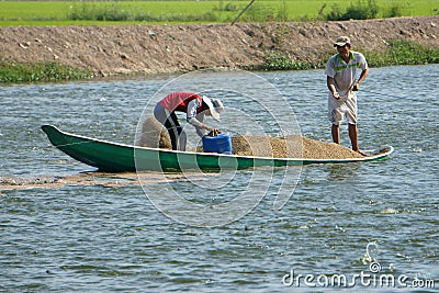 Asian farmer feeding, fish pond, fishery Editorial Stock Photo