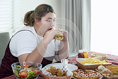 Asian fat girl hungry and eat a junk food on the table Stock Photo