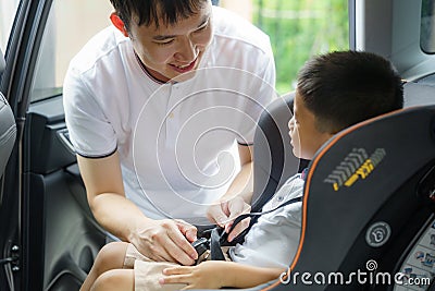 Asian father clicking child into car seat while traveling, fathers interact with their children throughout the day Stock Photo