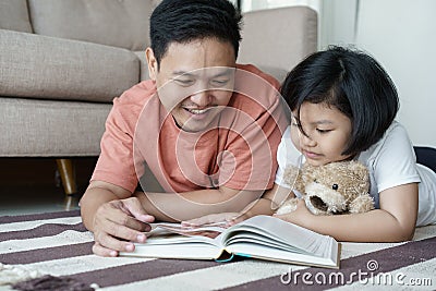 Asian father and daughter read books on the floor in the house, Self-learning concept Stock Photo