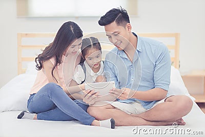 Asian father and mother watching cartoon with daughter Stock Photo