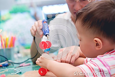 Asian Father teaching kid make a car toy with recycled materials, Little 2 years old toddler boy child make D.I.Y reuse toy with d Stock Photo