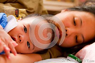 Asian female baby lying with her mother Stock Photo