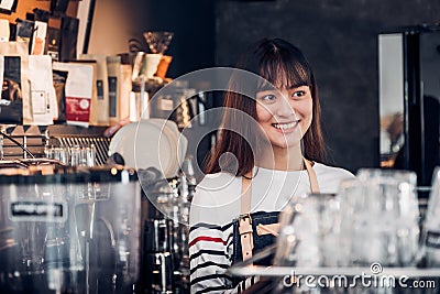 Asian female barista wear jean apron at counter bar with smile face, cafe service concept, owner business start up Stock Photo