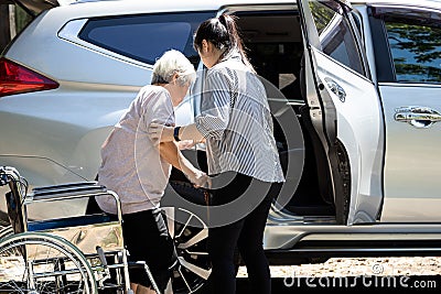 Asian female caregiver helping disabled elderly woman in wheelchair to get into the car,helpful daughter care and support senior Stock Photo