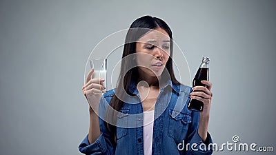 Asian female choosing between unhealthy beverage and useful healthy milk, diet Stock Photo