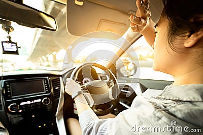 Asian female driver covering face by hand of bright sun,disturbed dazzled by sun light,difficulty in driving,young woman driving Stock Photo
