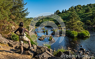 An asian female fly fisher women wearing waders, resting a rod on her shoulder Stock Photo