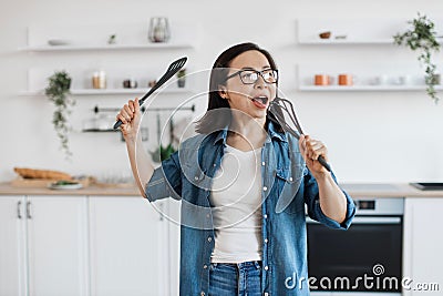 Asian female having fun with whisk while cooking at home Stock Photo