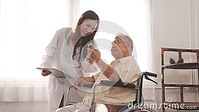 Asian female nurse tells how to take medicine to elderly senior grandfather patient Stock Photo