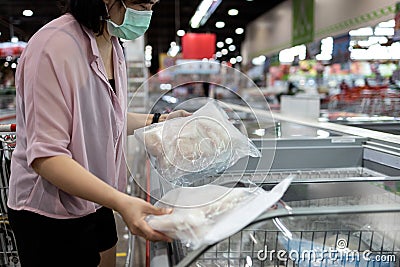 Asian female people choosing frozen seafood purchases frozen cut fish packages with fish in freezer in food department of Stock Photo