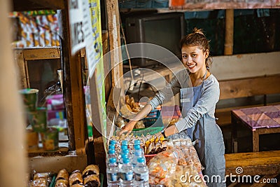 Asian female stall keeper arranges snacks on a table Stock Photo