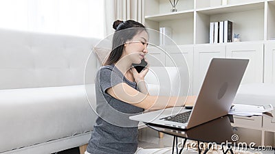 Asian female talking on the phone and working in a laptop with a smiling face, Business Cell Phone Conversations Stock Photo
