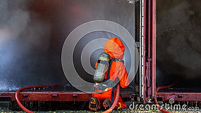 Asian firefighter on duty, Asian fireman spraying high pressure water, Fireman in fire fighting equipment uniform spray water from Stock Photo