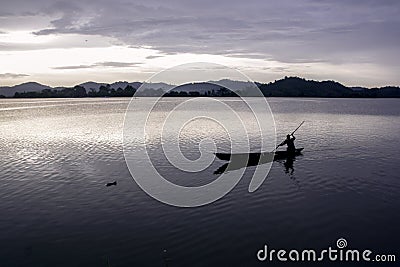 Asian fisherman boating across lake Stock Photo