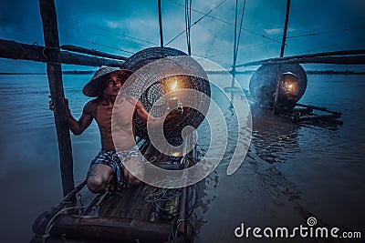 Asian fisherman holding a lantern on his boat waiting to fish in the Mekong Stock Photo