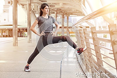 asian fitness young woman stretching leg on a rail bridge workout exercising on street in urban city . runner sport girl warm up Stock Photo