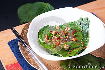 Asian food concept Homemade Korean organic Kkaennip Kimchi, PerillaShiso Kimchi in white ceramic bowl on wooden board with copy Stock Photo