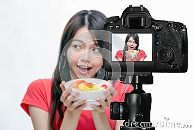 Asian food vlogger with fruit salad behind camera Stock Photo