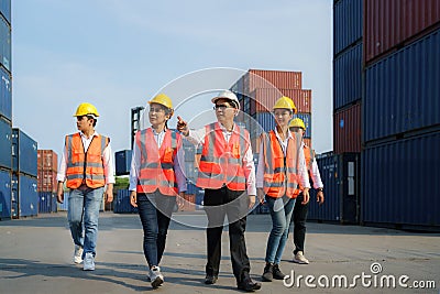 Asian foreman walking and explaining the various operations in the container depot terminal with four new trainees worker Stock Photo