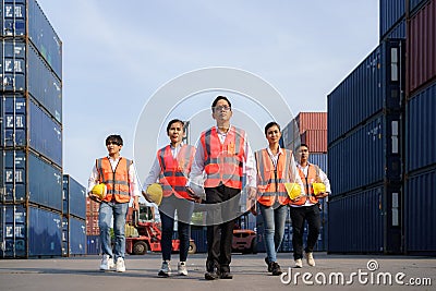 Asian foreman walking with four workers employee team after finishing work on the container depot terminal Stock Photo