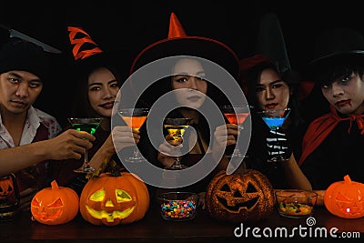 Asian friends in spooky costume having Halloween party celebration in nightclub and drinking cocktail drink together Stock Photo