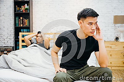 Asian gay couple having argument with each other in bedroom. Thoughtful gay man having stress while another is sleeping Stock Photo