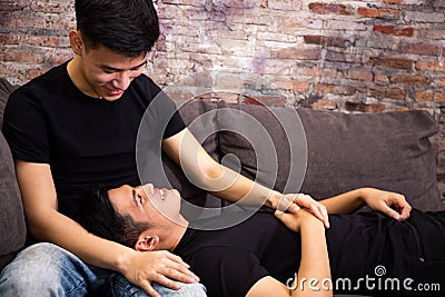 Asian gay couple looking at each other together on sofa at vintage home. Portrait of happy gay men - Homosexual love concept. Stock Photo