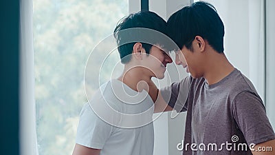 Asian Gay couple standing and hugging near the window at home. Young Asian LGBTQ+ men kissing happy relax rest together spend Stock Photo