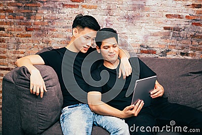 Asian gay couple watching and looking at phone tablet together. Portrait of happy gay men - Homosexual love concept. Stock Photo