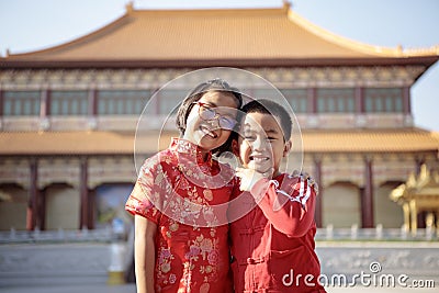Asian girl and boy wearing red chinese suit happiness against china temple background Stock Photo