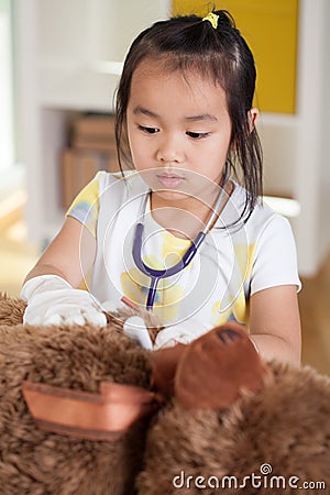 Asian girl examining teddy bear Stock Photo