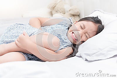 Asian girl feeling stomachache pain on bed, Stock Photo