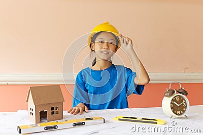 Asian girl has ambition to be a structural engineer with a helmet and the building plan put on the table. Stock Photo