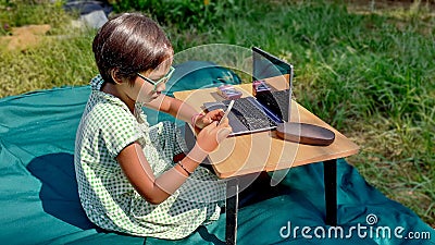 Asian girl look at smartphone learning from home with laptop and camera in the front yard. Editorial Stock Photo
