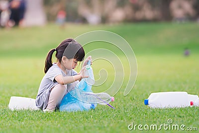 Asian girl is packing plastic bottle in bag. Children collect garbage to help maintain clean and beautiful environment. Stock Photo