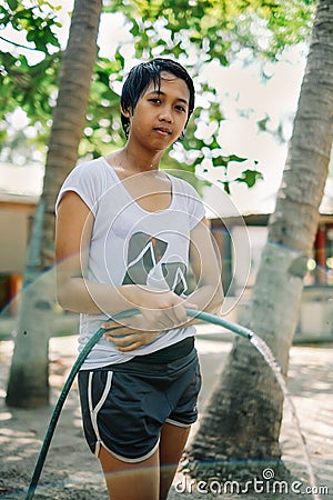 Asian girl showering with water hose on hot sunny day on the beach Stock Photo