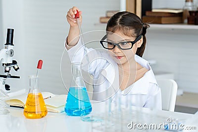Asian girl, small, sitting in science room, studying in science class, practical class, He was squeezing water from the flask, Stock Photo