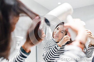 Girl smiles and dries her hair in the bathroom and looks in the mirror Stock Photo