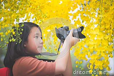 Asian girl take photo with blooming yellow flower Stock Photo